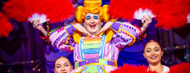 Dame Morgan Brind in a dance pose surrounded by bright feather fans