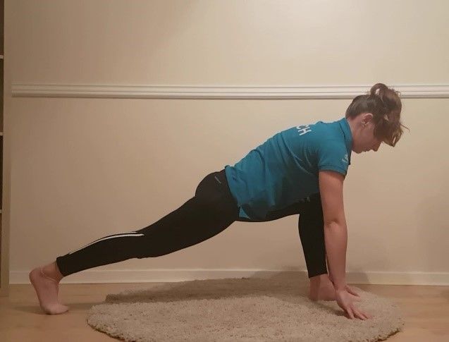 women in a plank position with one foot forward between hands