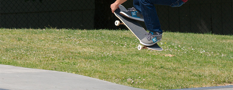 photograph of feet jumping off a ramp on a skateboard with grass in background