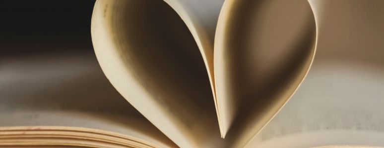 An open book with the inside pages turned over to make a heart shape.