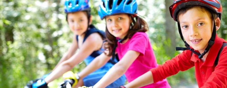 boys and girls on bikes on sunny day wearing cycle helmets