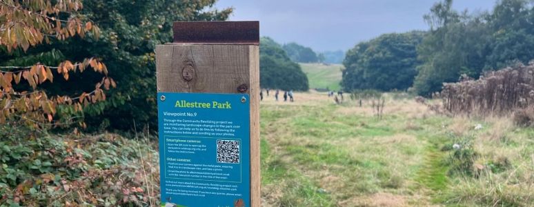 A wooden post at Allestree Park with a stand for a camera and a poster with instructions