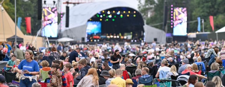 A crowd gather in front of an outside stage.