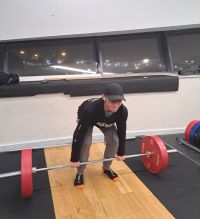 image shows Callum in a gym setting lifting weights