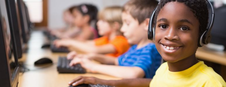 Boy at computer with headphones on in library