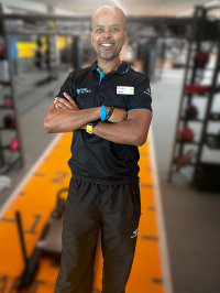 Abdul standing in front of a image of a gym