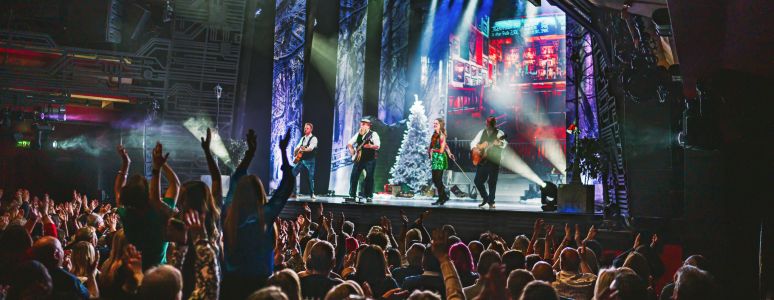 A crowd dances with an band and dancers on stage