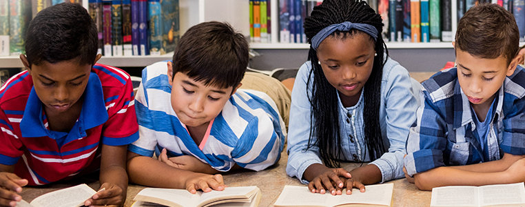 Four children sit on the floor reading