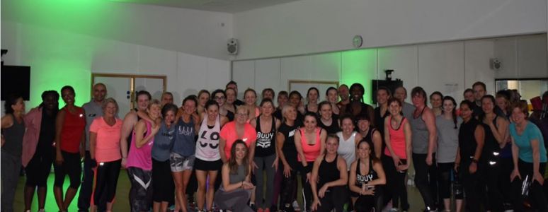 Group of people in fitness clothes, in a room lit with green spotlights