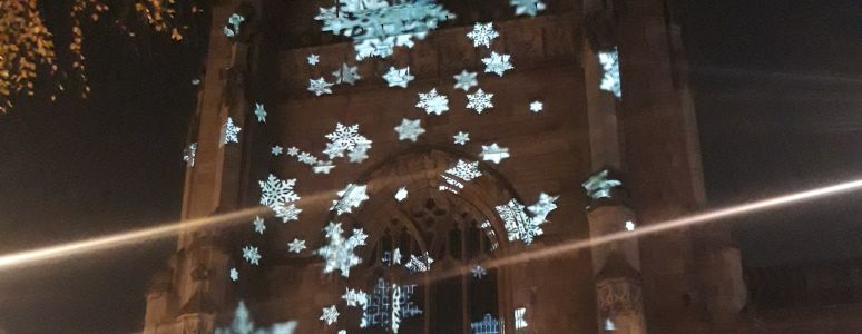 light projections of stars across the tower of Derby Cathedral at night