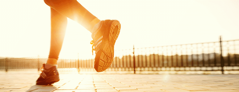 runners feet with bright sunshine on the horizon