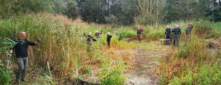 happy volunteers standing round the pond
