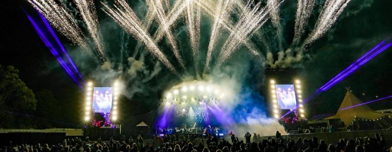 A photograph showing a large crowd during the Darley Park Concert, with golden lights shining above them