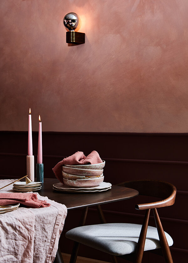 Photography: Lol Johnson Photography @still_loljohnsonphotography Tightly cropped shot of pink dishes and candles on a Corso table in front of a pink wall