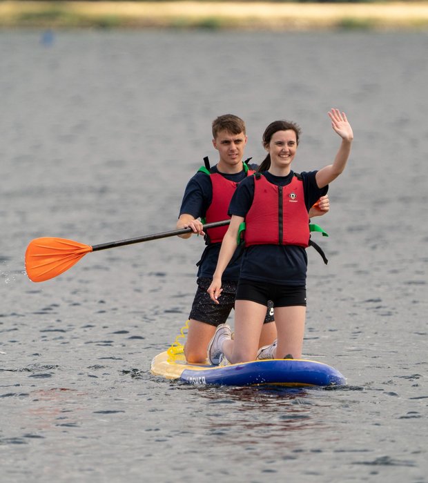 sharing paddleboard and waving
