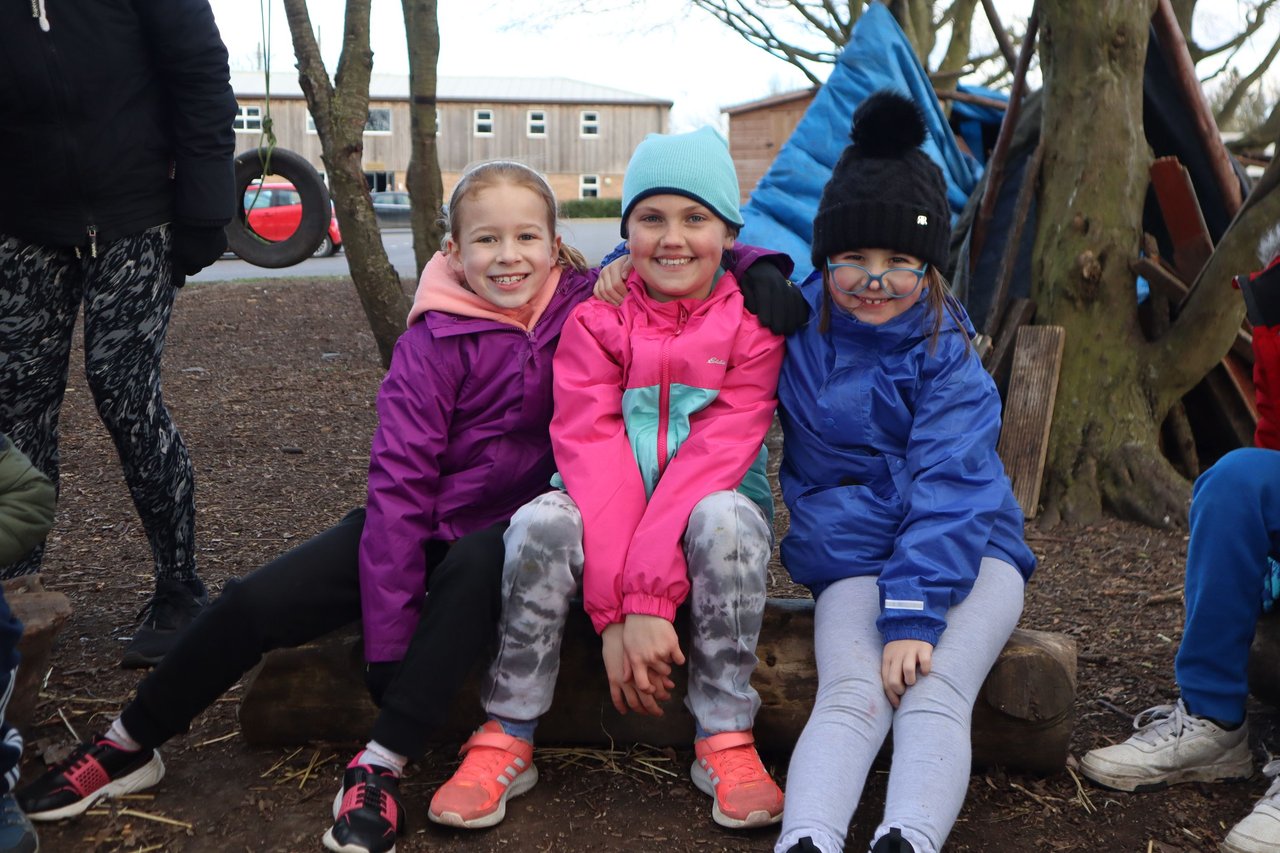 three girls sitting for picture in bushcraft