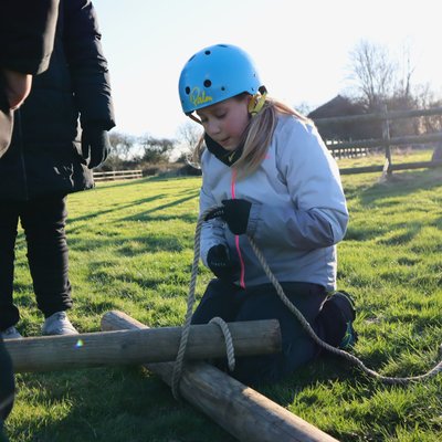 girl using rope to tie poles together