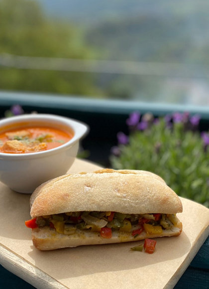 A panini and a bowl of soup on a wooden board
