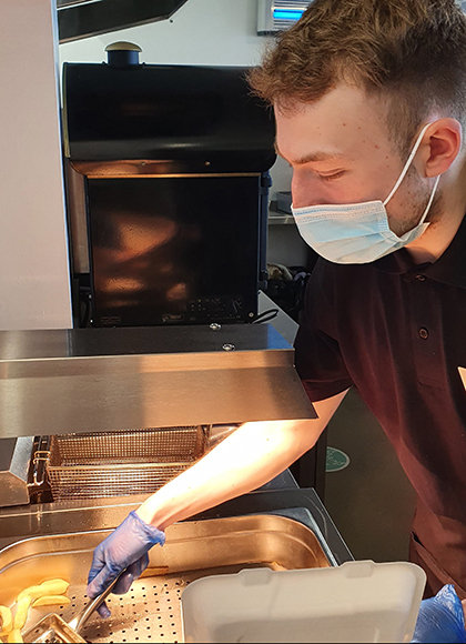 A member of serving staff dishing up some chips