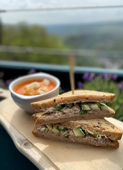 A tuna and cucumber sandwich and a bowl of tomato soup with croutons