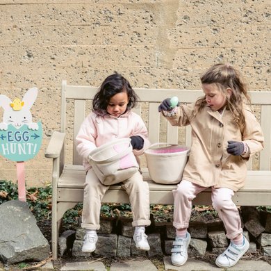 Girls sitting on a bench with easter egg hunt baskets