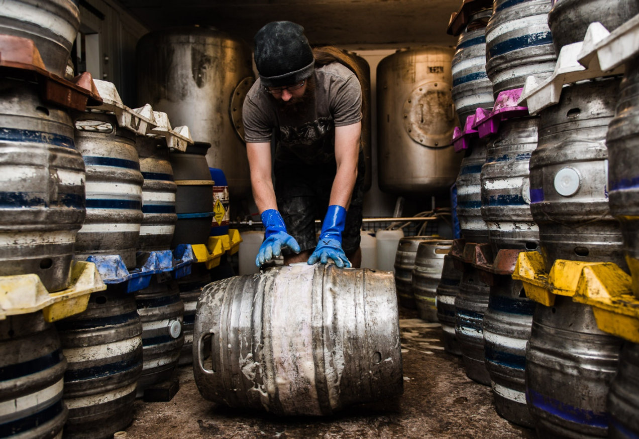 Man rolling beer barrel inside brewery