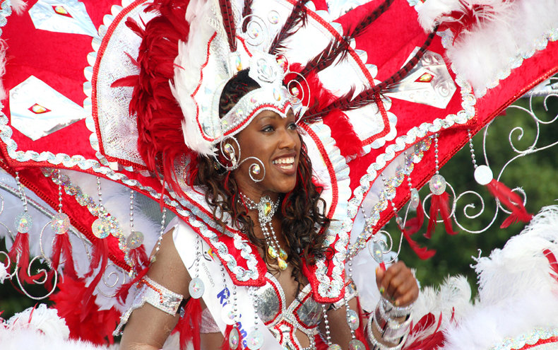 Lady performer dressed in bright extravagant costume for the Derby Caribbean Carnival