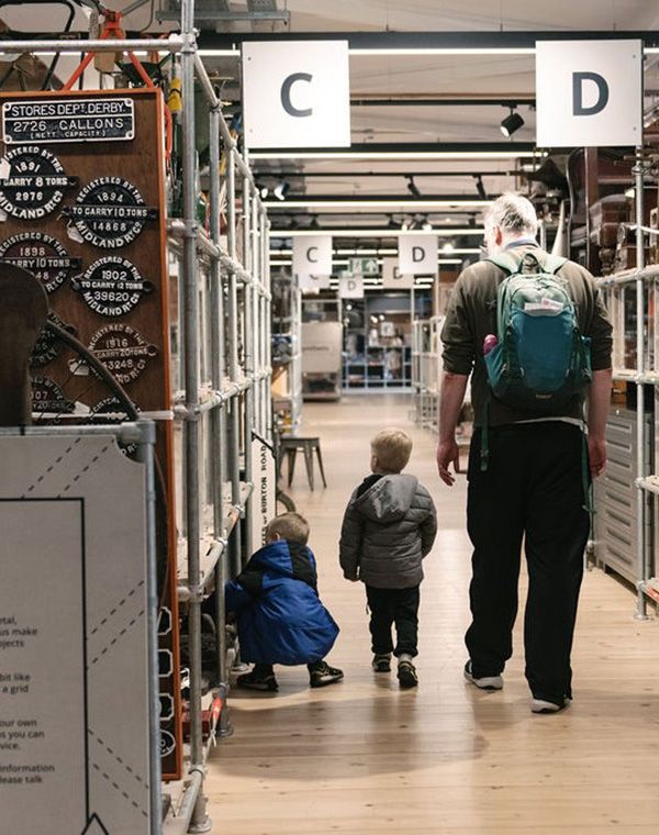 A man with two small boys walks away from the camera inside Derby's Museum of Making