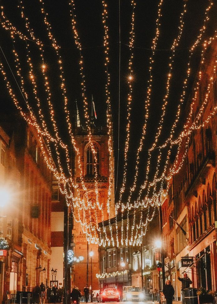 Strings of festive lights hanging above Iron Gate in Derby at night, looking towards Derby Cathedral
