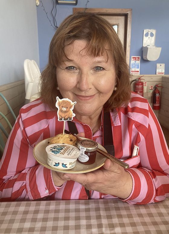 A woman holding up a plate of Highland Afternoon Tea