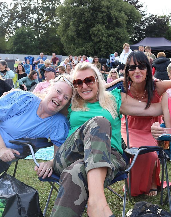 Three people sitting and enjoying an outdoor festival
