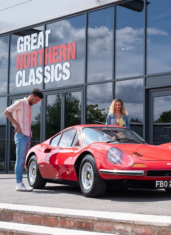 A couple looking at a red sports car