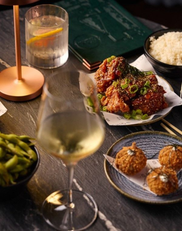 A glass of white wine and a selection of tasty looking food on a wooden table
