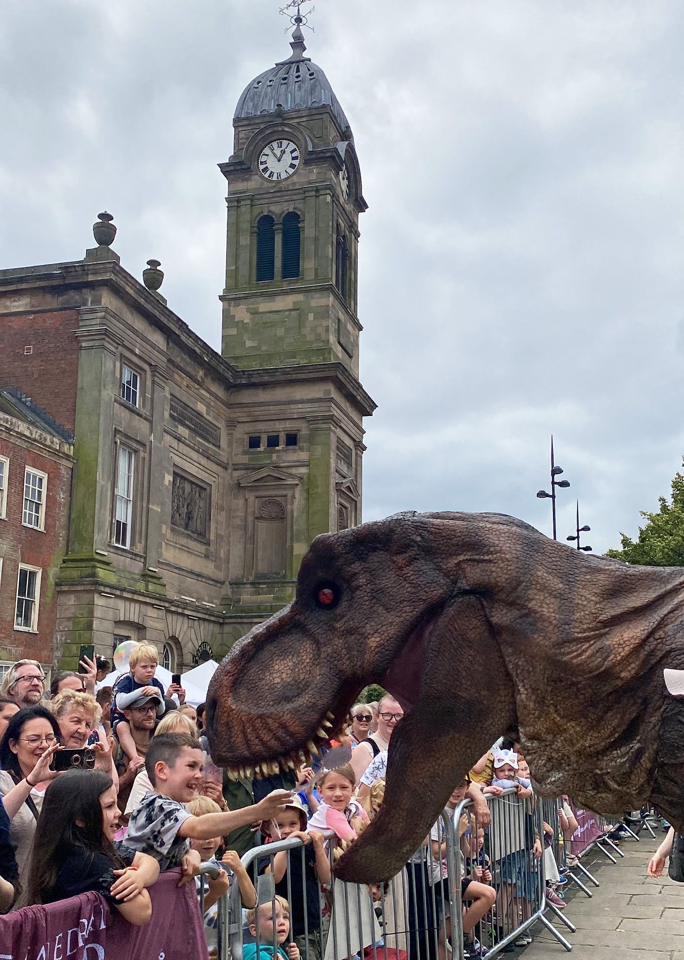 Dinosaur entertaining a crowd in front of the Guild Hall