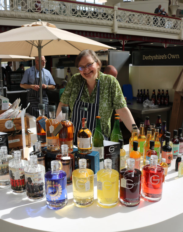 A woman proudly displaying a large selection of local drinks in colourful bottles