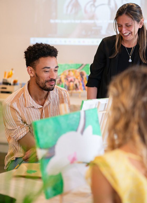 Three people in an art class painting colourful pictures