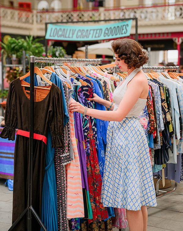 A woman browsing a rail of vintage clothing