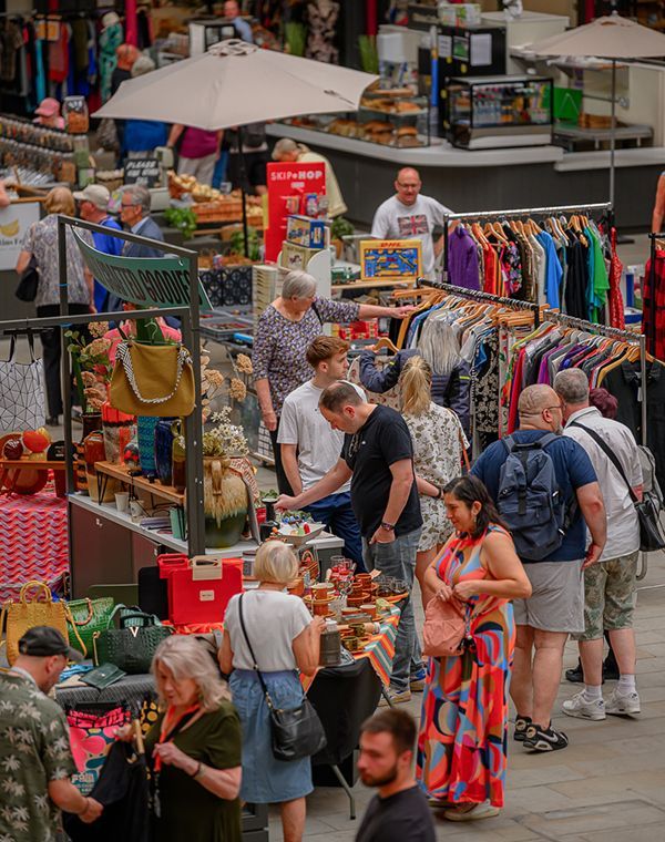 A bustling market scene with diverse shoppers exploring various stalls filled with unique items and vintage treasures.