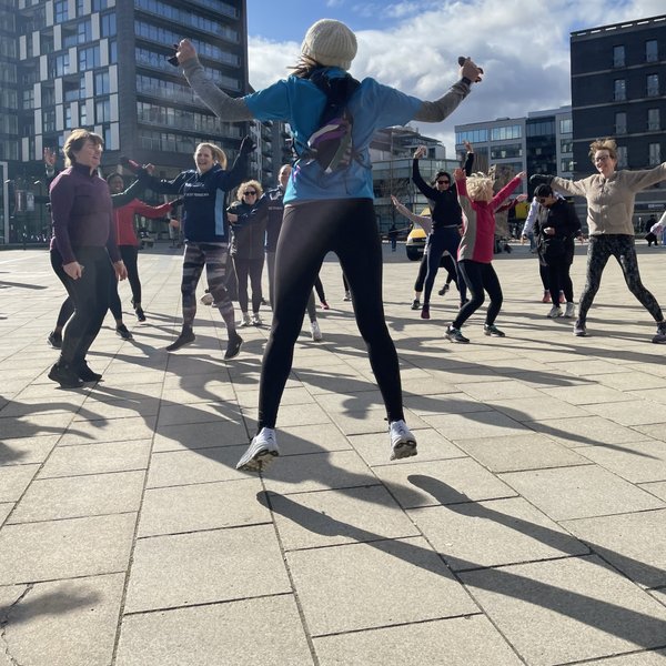 A diverse group of people joyfully dancing in a bustling city square