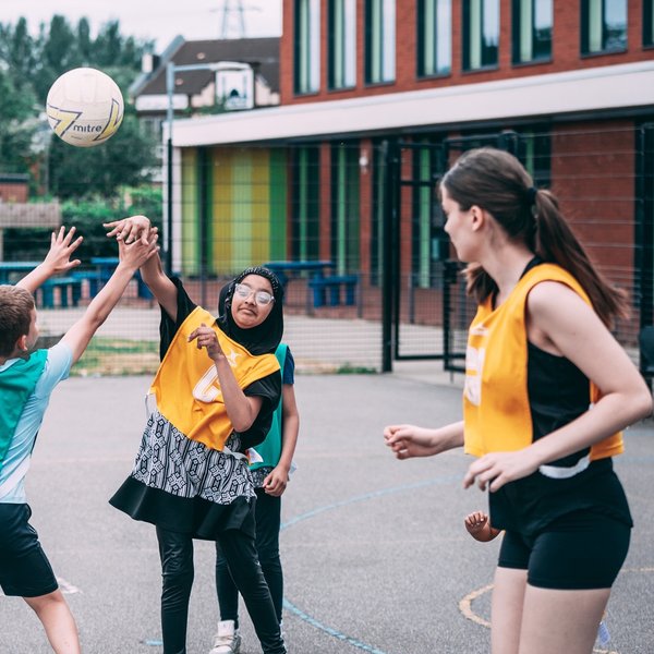 Group of young people playing netball on an outdoor court