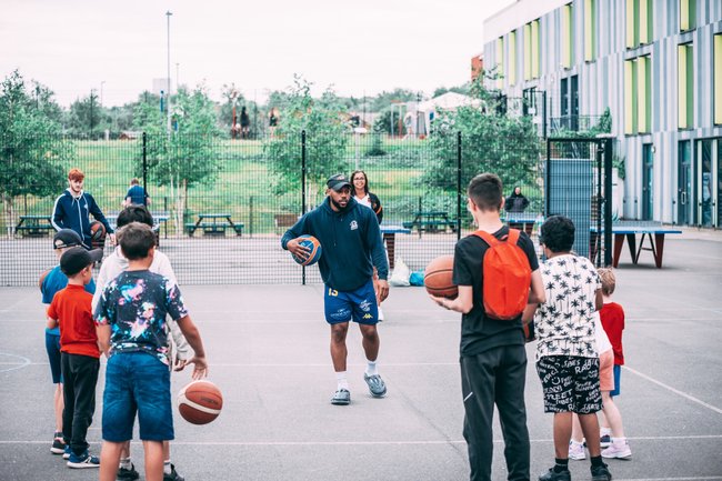 A group of young people playing basketball on a court.