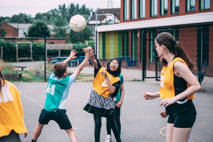A diverse group of young women playing netball on an outdoor court
