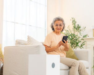 Older South Asian adult using a voice-activated smart speaker at home