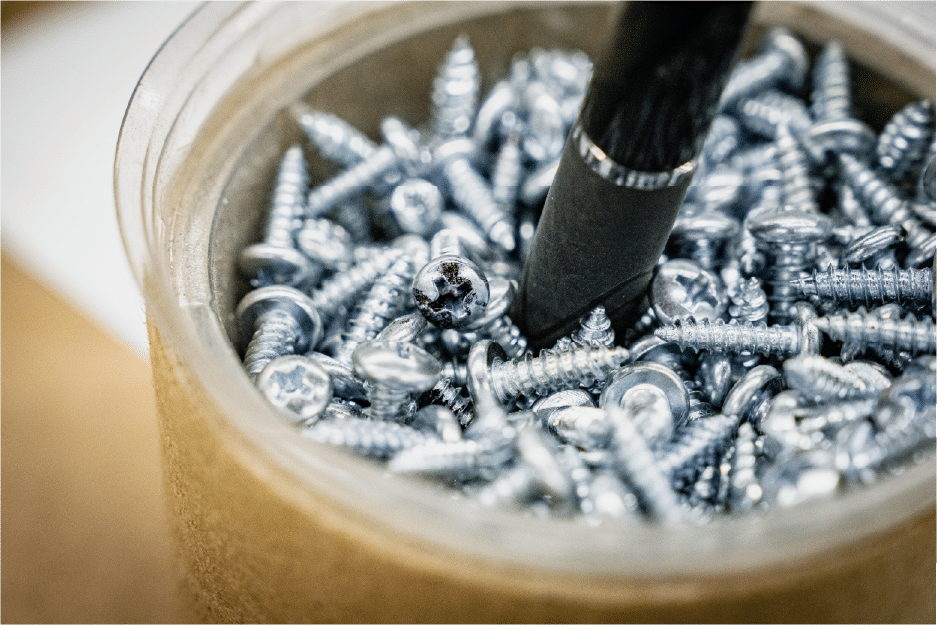 Screwdriver resting in container filled with metal screws