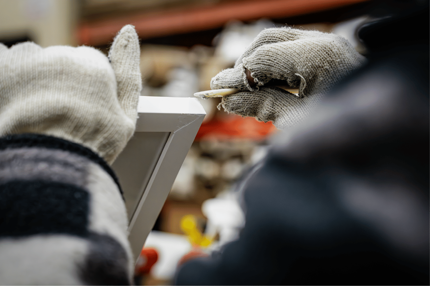 Gloved hands smoothing frame edge with tool