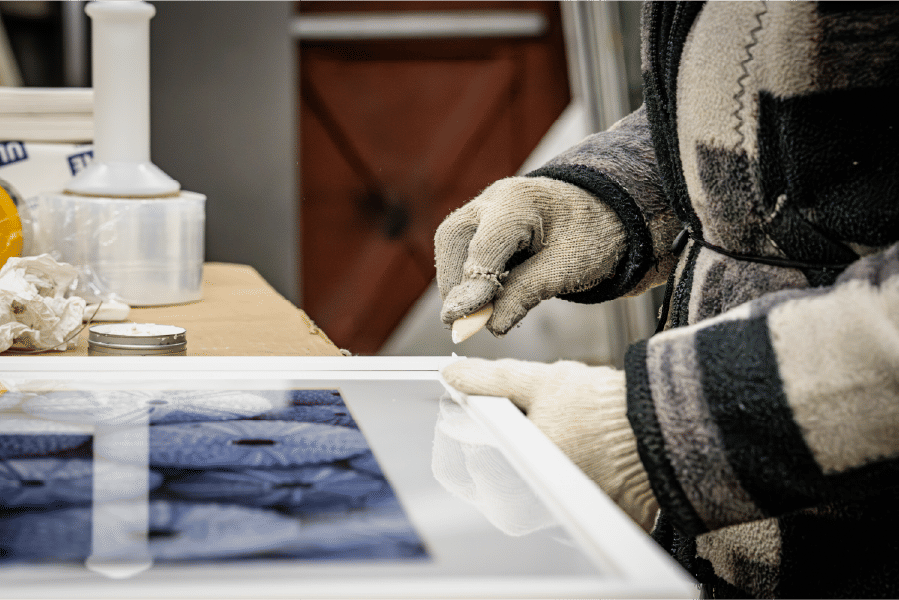 Worker smoothing adhesive on frame corner