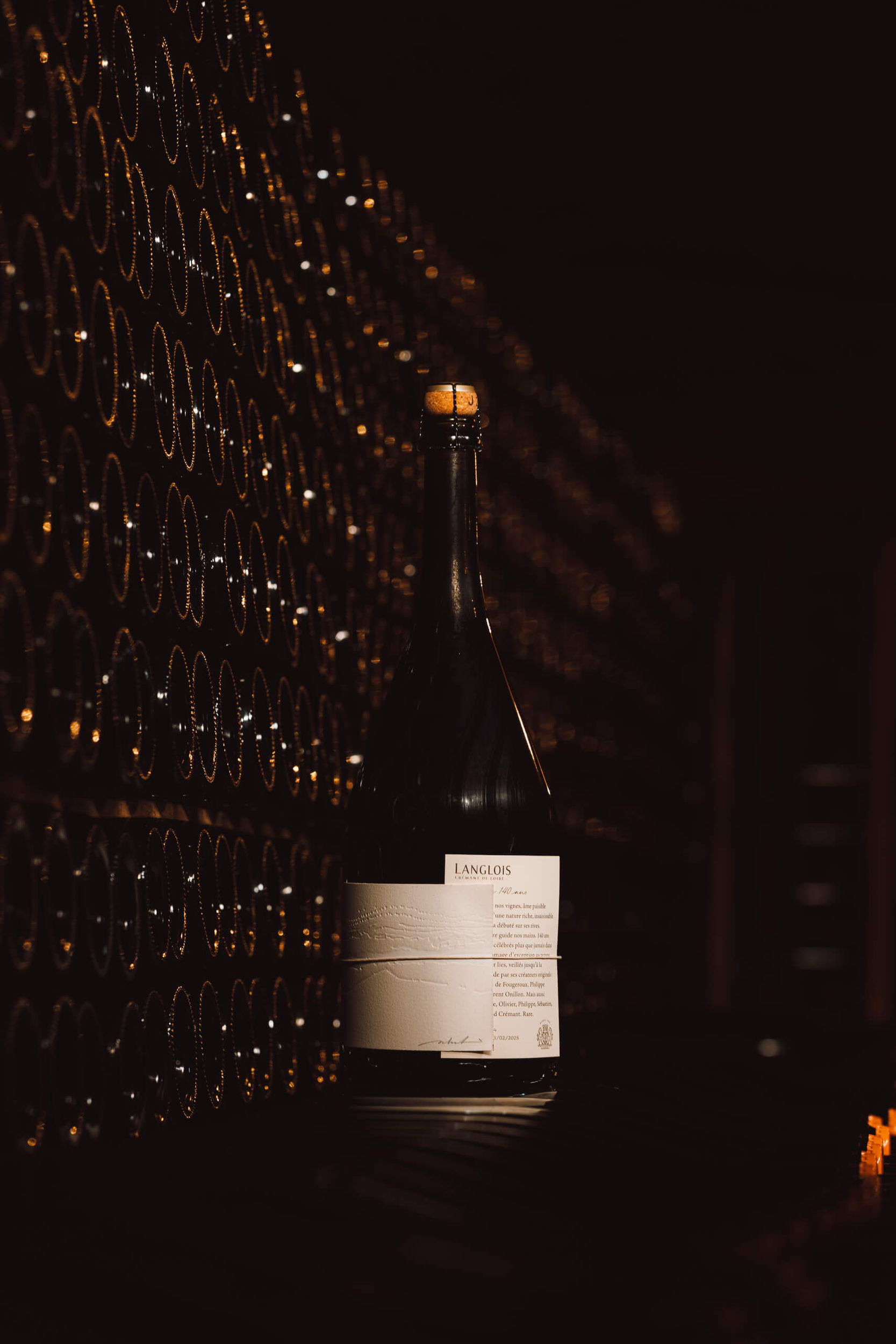 Langlois, Cadence Extra Brut 140 ans devant des bouteilles de Crémant de Loire Langlois en élevage sur lies dans les caves