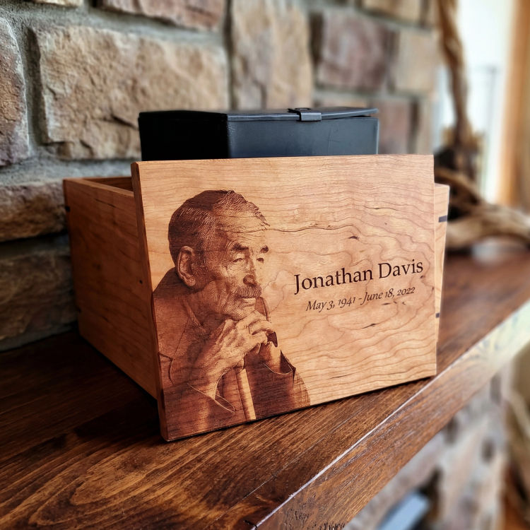 Close-up of a custom-engraved large hardwood maple cremation urn, featuring a portrait and personalized text.