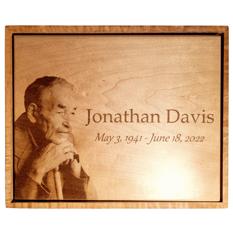 Close-up of a custom-engraved large hardwood maple cremation urn, featuring a portrait and personalized text.