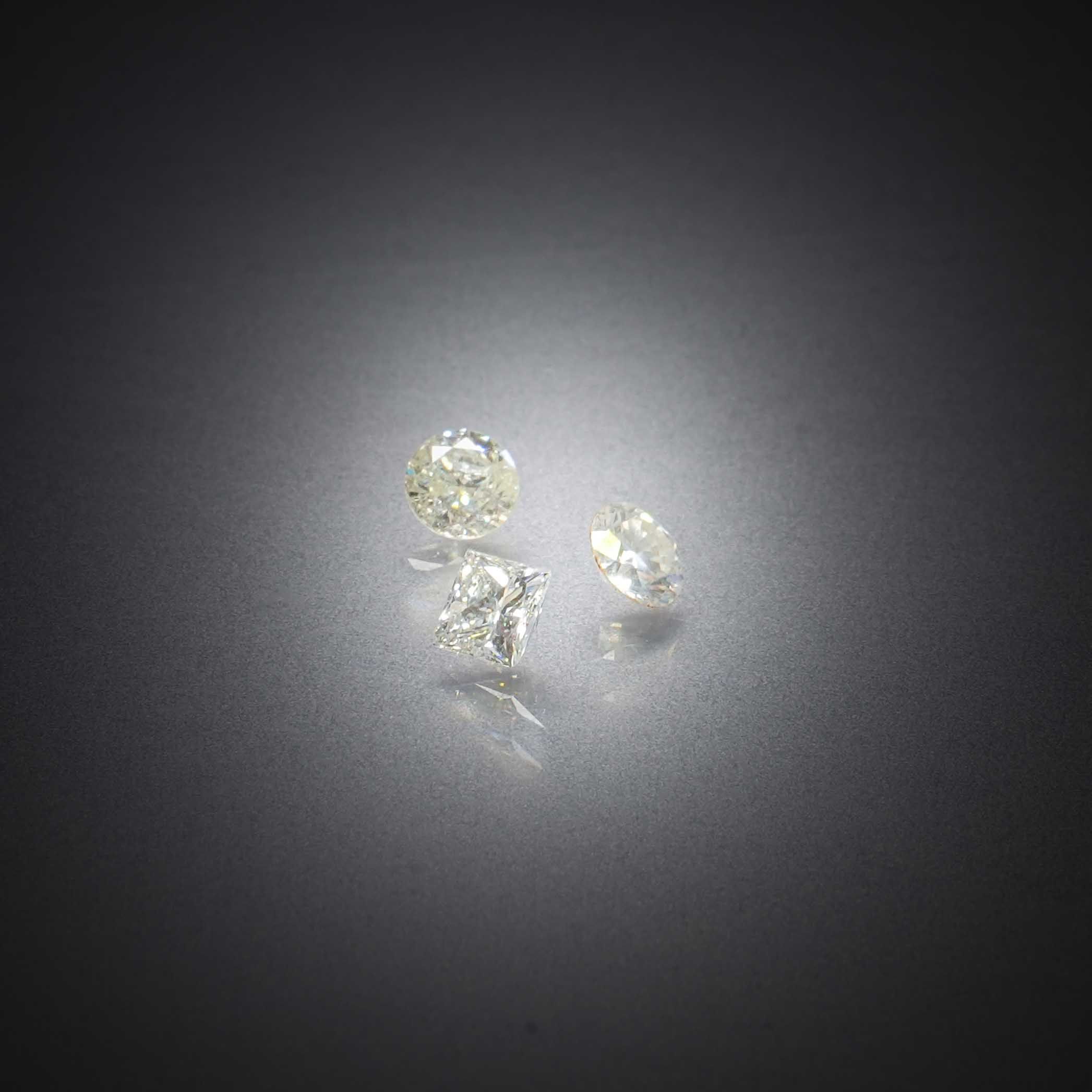 Lot de trois diamants, deux ronds et un princesse, sur papier. - Lazuli